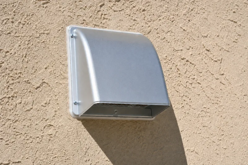 New rigid metal dryer vent duct being installed through a wall in a Gilbert, AZ home